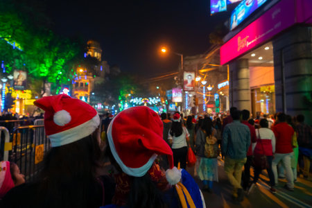 Kolkata, West Bengal, India - 26.12.2018 : Young ladies with red santa claus hats enjoying themselves at illuminated and decorated park street with lights with year end festive mood.のeditorial素材