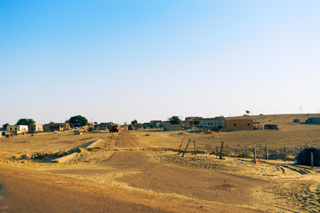 Empty road approaching remote desert village inside the desert. Distant horizon, Hot summer at Thar desert, Rajasthan, India.のeditorial素材