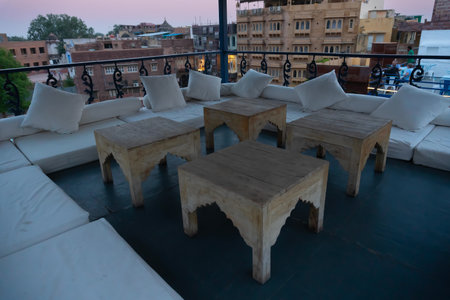 Decorated interior view of a roof top restaurant with wooden tables and cushions for relax of customers. Jodhpur, Rajasthan, India.の写真素材