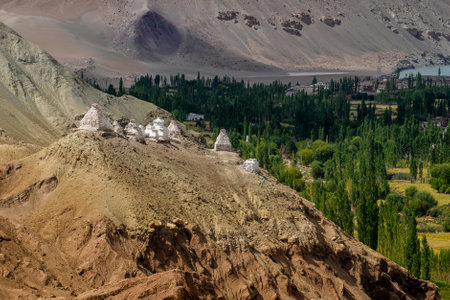 Buddhist Stupa, mound-like or hemispherical structure containing relics , used as a place of meditation. Green trees and Himalayan mountains in the background. Leh, Uninion territory of Ladkah, India.の写真素材