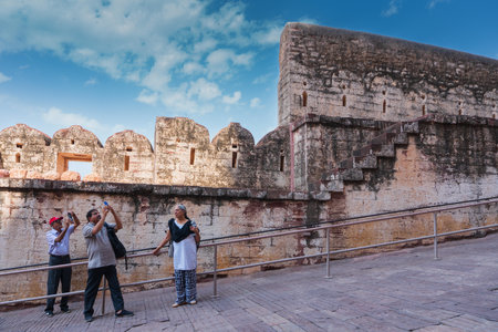 Jodhpur, Rajasthan, India - 19th October 2019 : Indian tourists taking picture of Mehrangarh fort with their mobile phones while older woman looks and enjoys their happiness. Mehrangarh fort yard.のeditorial素材
