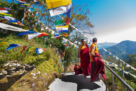 Samdruptse Monastery, Ravangla, Sikkim, India - October 20, 2016 : Happy Monks laughing, flying colourful Buddhist religious prayer flags with green leaves and blue sky in background, Sikkim, Indiaのeditorial素材