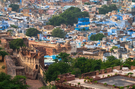 Top view of Mehrangarh fort with distant view of blue city Jodhpur, Rajasthan, India. Blue sky with white clouds in the background. One of the seven gates to enter the huge fort is seen below,のeditorial素材