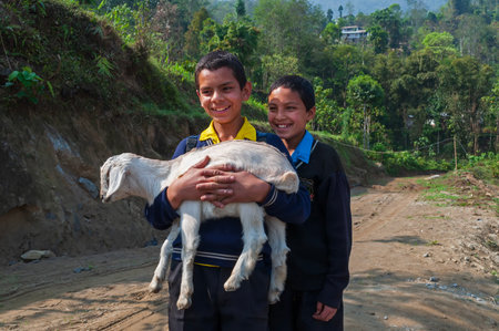 Sikkim, India - 22nd March 2004 : Two school boys in uniform are carrying their pet goat and smiling in happiness. Sikkim has one of the most educated population with high literacy rate.のeditorial素材
