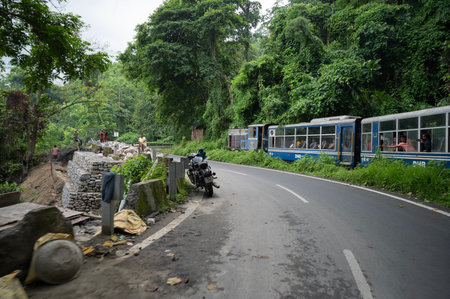 Darjeeling,West Bengal,India - 10th August 2023 : Himalayan road being constructed by workers while Diesel Toy train passing through jungle beside. Darjeeling Himalayan Railway, narrow gauge railway.のeditorial素材