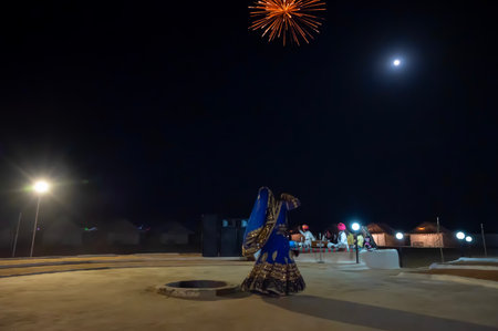 Thar desert, Rajasthan,India - October 15th 2019 : Rajasthani female, dancing in cultural dress of Rajasthan, at night. Musicians are playing in moonlit night with fire crackers bursting in night sky.のeditorial素材