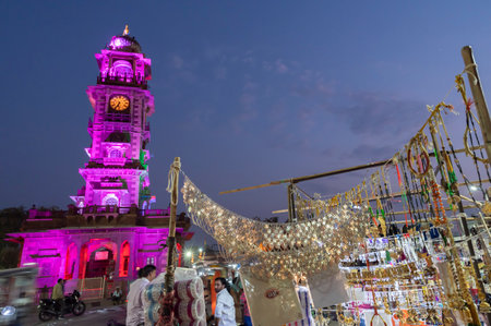 Jodhpur, Rajasthan, India - 19.10.2019 : Gold and silver plated ornaments, bangles, jewelry are being sold at famous Sardar Market and Ghanta ghar Clock tower in afternoon. Blue hour.のeditorial素材