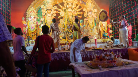 Howrah, West Bengal, India - 5th October, 2022 : Hindu Purohits offering Vog, holy sweet food to Goddess Durga while Dhaakis playing dhaaks, inside Durga puja pandal covered with holy smoke.のeditorial素材