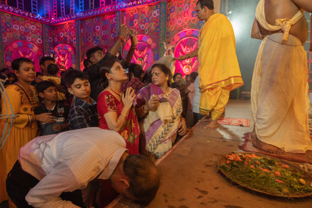 Howrah, West Bengal, India - 3rd October, 2022 : Hindu Bengali sari clad women praying to Goddess Durga inside Durga Puja pandal. Ashtami puja aarati at night. Biggest fetsival of Hinduism.のeditorial素材