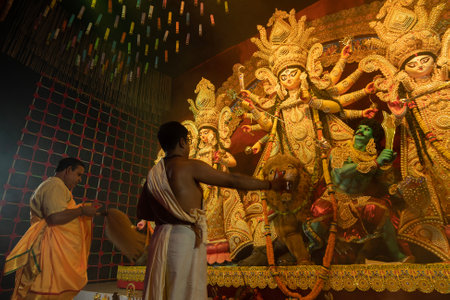 Howrah, West Bengal, India - 3rd October, 2022 : Hindu Priests worshipping Goddess Durga with shaari, traditional Bengali womens dress. Ashtami puja aarati - Durga Puja ritual- festival of Hinduism.のeditorial素材