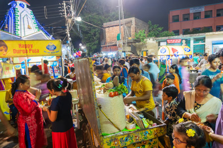 Howrah, West Bengal, India - April 14th 2019 : Hindu bengali devotees eating velpuri, a roadside Indian bengali food dish, celebarting bengali new year known as Gajan or Charak festival , at night.のeditorial素材