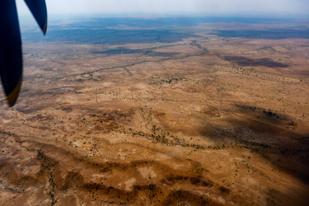 View of a desert from an aeroplane. The propellers and the desert in the frame. Play of sun light and clouds shadow on the desert below.の写真素材