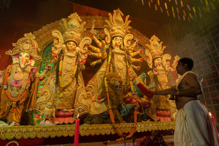 Howrah, West Bengal, India - 3rd October, 2022 : Hindu Priests worshipping Goddess Durga with gaamchaa, traditional thin, coarse cotton towel. Ashtami puja aarati - sacred Durga Puja ritual.のeditorial素材