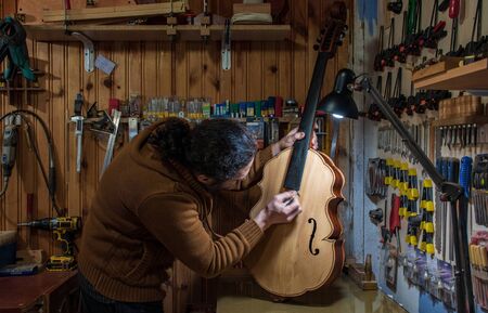 luthier making a custom handmade cello in workshop at nightの写真素材