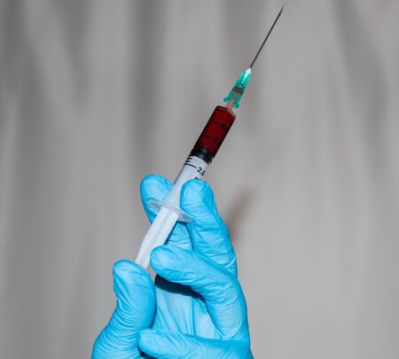 injector with blood sample on the hand of a female doctorの写真素材