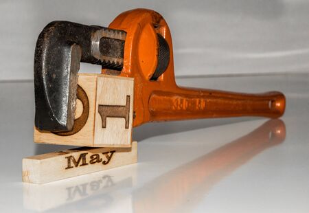 a pipe wrench compressing wooden cube "first of may" - labor day theme with wooden calendar cubes / blocksの写真素材