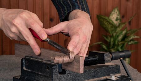 closeup scene of hands of a male wood worker, shaping wooden plank with chisel - locked in the viseの写真素材