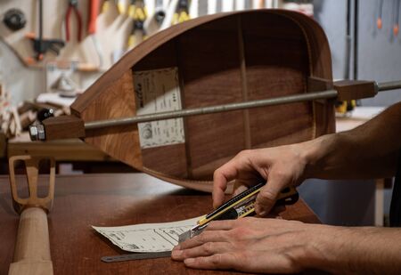 a closeup scene of luthier's hands cutting handmade titles for wooden musical instrumentsの写真素材
