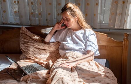 a young lady in the bed watching something at early morning with gentle sunlightの写真素材