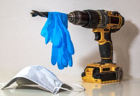 a worker tool hand drill with blue disposable gloves and medical maskの写真素材