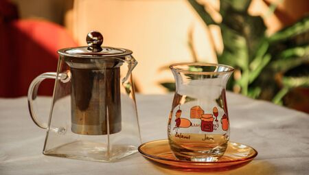 an empty glass teapot and classic turkish tea glass on the table, alive colorful closeupの写真素材