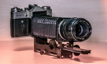 old used vintage SLR camera with macro bellows (adjustable accordion platform) from CCCP, isolated on red light closeup sceneの写真素材