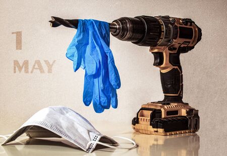a worker tool hand drill with blue disposable gloves and medical mask - theme of the labor day in the shadow of coronavirusの写真素材