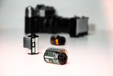 unused 35 mm BW film rolls perspective preferentially placed on the white platform with an ancient camera in blur background with unusual film dublicator lensの写真素材