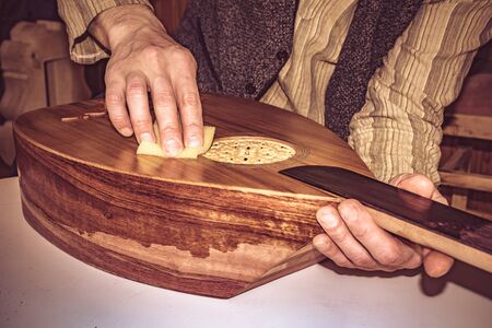 an instrument maker applying shellac, french polish onto the authentic instrument of middle eastの写真素材