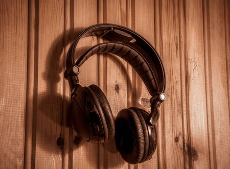 wireless headphone / earphone hanging on the wooden wall, stays overlay alike within creamy atmosphereの写真素材