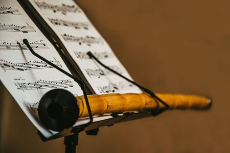 closeup scene of an oriental musical instrument Ney, stays on the music sheet stand with notes, isolated, mystic scene, traditional eastern and turkish folk music materialsの写真素材