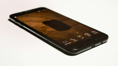 a black smartphone focus on the messages icon, retro styled touchscreen isolated on the white background, perspective view.のeditorial素材