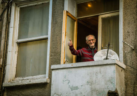 Concept of corona virus issue, stay at home, conjuncture of lockdown for elders. an old man in balcony says hi to outdoor life.のeditorial素材