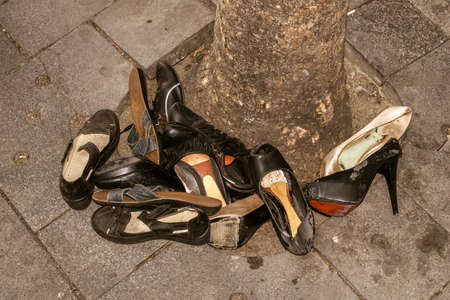 old shoes thrown at the bottom of a tree on the street, closeup. night light.