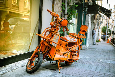 an almost scrapped modified scooter, retro city bike, painted all orange, phosphorous, stays as an offbeat object on the street.の写真素材