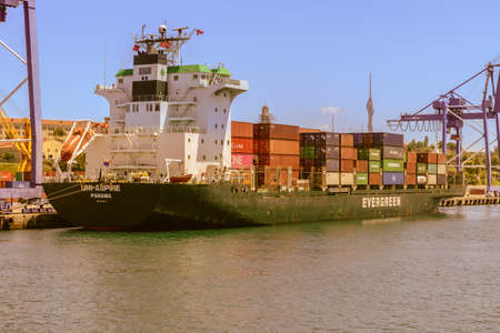 an international freight ship fully loaded with colorful containers, waiting in port.のeditorial素材