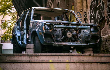 an abandoned scrap car, standing apart on the sidewalk, outdoor.の写真素材