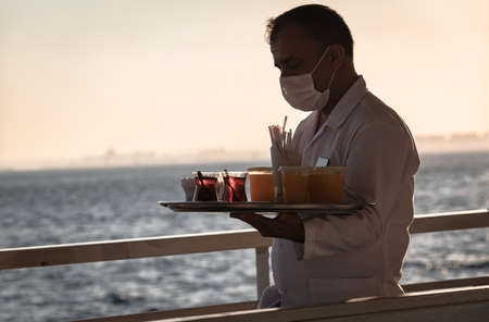 Istanbul/Turkey - July, 2020: man with mask is serving tea and cold drinks on board, working in a ferryboat. new normality.のeditorial素材