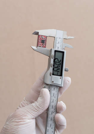 man measuring a microchip with electronic precision caliper, hands only, extreme close-up.の写真素材