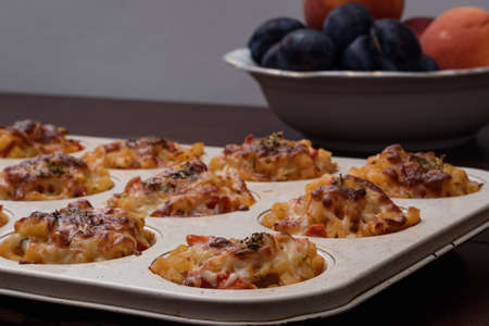 Pasta balls to be served with melted cheddar cheese sauce in the oven, some fruits in blur background.の写真素材