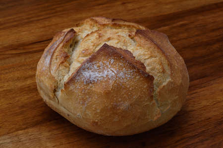 Thick crust organic round village bread on the brown wooden platform, close-up.の写真素材
