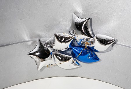Six star silver and blue balloons with golden ribbons under ceilingの写真素材