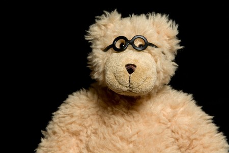 Teddy bear in glasses close up portrait on black backgroundの写真素材