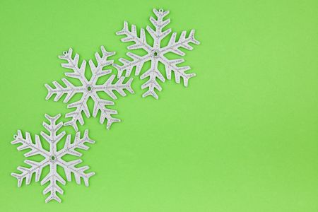 Three Christmas decoration silver snowflakes on green background. Useful for any type of Christmas cardの写真素材