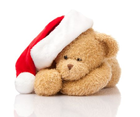 Christmas teddy bear in Santa cap laying on whiteの写真素材