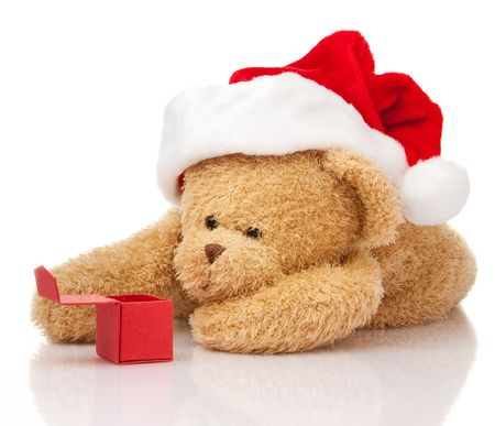 Christmas teddy bear in Santa cap with gift box laying on whiteの写真素材