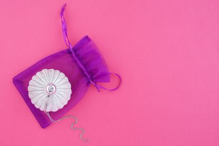 Christmas decoration silver ball with silver chain and lilac bag on pink background with empty place for your textの写真素材