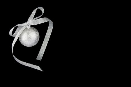 Christmas decoration silver ball with silver ribbon on black background with empty place for your textの写真素材