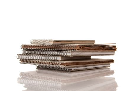 Pile of Old Spiral Note Pads on White Background with reflectionの写真素材