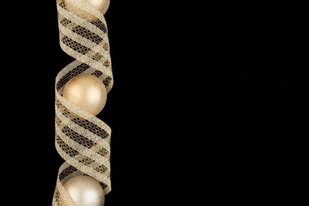 Christmas decoration gold balls with gold ribbon on black background with empty space for your textの写真素材